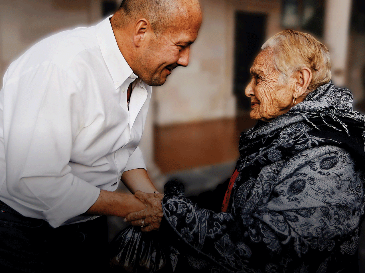 Foto del gobernador Enrique Alfaro platicando con un señora de la tercera edad.